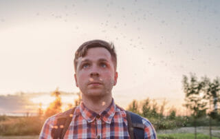 Man with bugs flying around his head